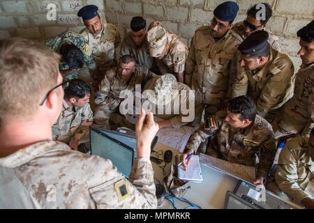 L'avant du Corps des Marines des États-Unis d'observateurs déployés à l'appui de la Force opérationnelle interarmées - Fonctionnement résoudre inhérent et affecté à la 4e Compagnie de liaison Naval, enseigne aux soldats des forces de sécurité irakiennes les fondamentaux de la lecture de carte pendant l'appel pour la formation de tir indirect au Camp Manion, l'Iraq, le 1 avril 2017. Les forces de la Coalition sur l'ISF train compétences de combat avancé à l'appui de la CJTF-OIR, la Coalition mondiale pour vaincre ISIS en Iraq et en Syrie. (U.S. Photo de l'armée par la CPS. Christopher Brecht) Banque D'Images