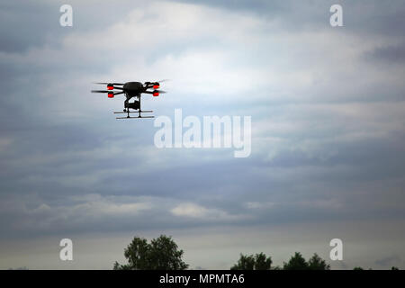 Un drone quadcopter en vol au dessus de la cime des arbres contre moody sky. Banque D'Images