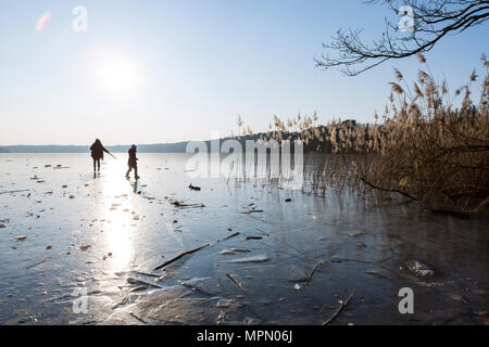 Allemagne, Brandebourg, lac Straussee, lac gelé et les silhouettes de deux personnes marchant sur la glace Banque D'Images