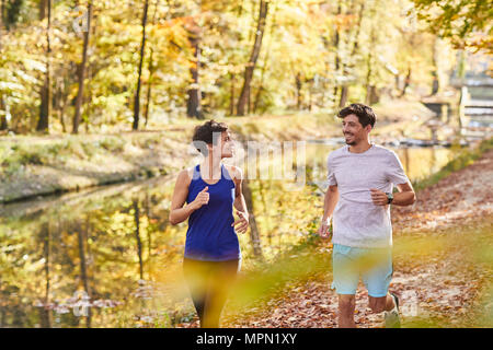 Couple jogging sur la piste forestière autumnally Banque D'Images