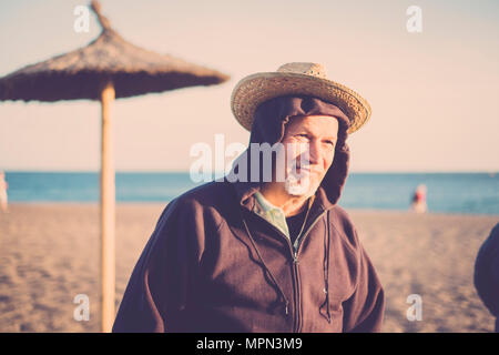 Belle funny senior homme à double casquette à la plage en hiver. vintge tons. sourire et lumière sur le visage ensoleillé Banque D'Images