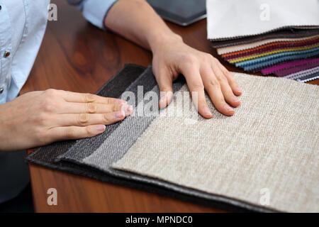 Les tissus de recouvrement . La femme regarde les couleurs et les motifs des tissus d'ameublement. Banque D'Images