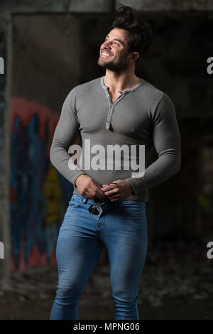 Portrait d'un jeune homme en bonne forme physique en gris à manches longues montrant son corps bien formé - Remise en forme musculaire Bodybuilder Athletic Model Posing Af Banque D'Images