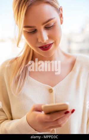 Blonde woman using smartphone à la maison Banque D'Images