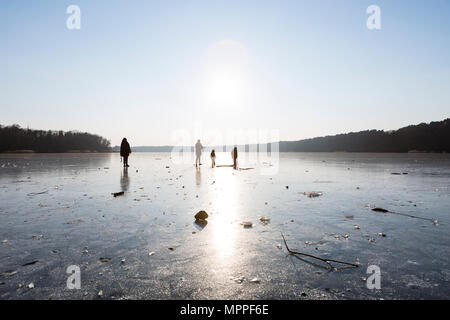 Allemagne, Brandebourg, lac Straussee, lac gelé et des silhouettes de personnes marchant sur la glace Banque D'Images