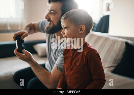 Happy little boy playing computer jeu avec son père à la maison Banque D'Images