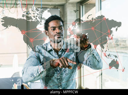 Businessman touching vitre avec carte du monde in office Banque D'Images