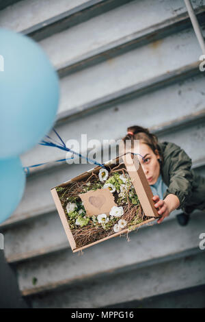 Envoyer femme présents dans boîte en carton avec des ballons Banque D'Images