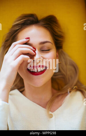 Smiling blonde woman lying on sofa Banque D'Images