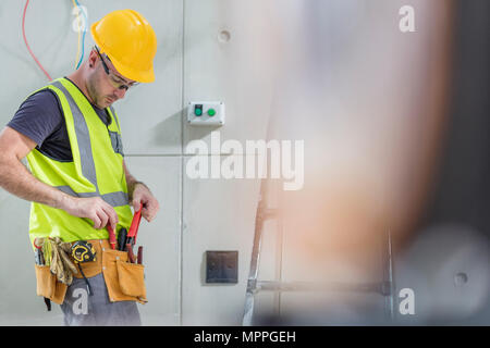 Outils d'électricien en tenant hors de la ceinture de sécurité sur chantier de construction Banque D'Images