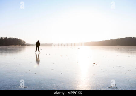 Allemagne, Brandebourg, lac Straussee, lac gelé et silhouette d'un patineur sur glace Banque D'Images