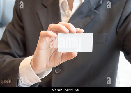L'homme en costume sitting at table showing blank white carte immersive Banque D'Images