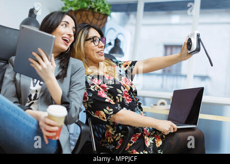 Deux professionnels des jeunes femmes dans le bureau en tenant un selfies Banque D'Images