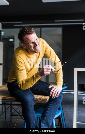 Happy businessman sitting on table à l'écart Banque D'Images