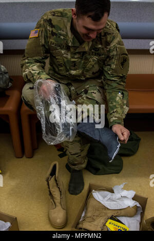 Réserve de l'Armée US 1er lieutenant Zachary Daugherty, officier du renseignement et à la 325e compagnie d'opérations psychologiques tactiques (Airborne), 2e Groupe d'opérations psychologiques, examine et assure l'ajustement d'un démarrage par temps froid avant d'insérer la question à la Fort McCoy, Wisconsin Question centrale Installation dans la préparation à la formation et à la qualification lors de l'opération d'acier froid, Avril 03, 2017. Le 2e Groupe d'opérations psychologiques et trans-régional associe les compétences régionales, politiques et militaires et de sensibilisation à la communication interculturelle compétences pour mener et soutenir des opérations civiles et militaires pour conven Banque D'Images