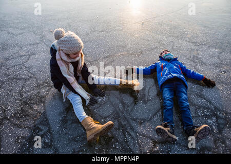 Allemagne, Brandebourg, lac Straussee, deux enfants assis et couché sur le lac gelé Banque D'Images