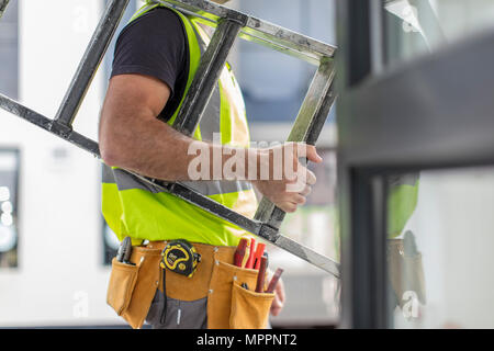 Close-up of construction worker carrying ladder Banque D'Images