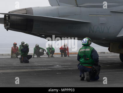 Le 5 avril 2017, à bord du porte-avions USS Nimitz (CVN 68), des marins se préparent à lancer un EA-18G Growler de l'Electronic Attack Squadron 142, connu sous le nom de Gray Wolves. Le Growler est un avion de guerre électronique embarqué propulsé par deux turboréacteurs F414-GE-400. Le navire effectuait un exercice composite Training Unit Exercise (COMPTUEX) avec le Nimitz Carrier Strike Group pour tester la préparation à la mission et la capacité à fonctionner en tant qu'unité intégrée au moyen de scénarios opérationnels simulés. Banque D'Images