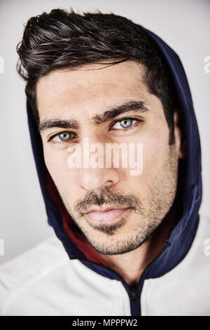 Portrait de jeune homme sérieux avec les yeux bleus et portant des chaumes hoodes jacket Banque D'Images