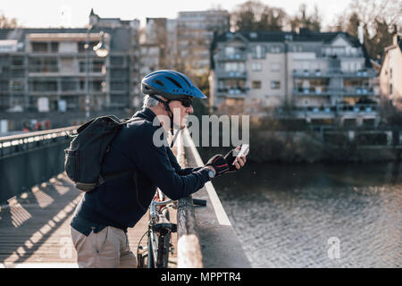 Man avec le port du casque pour l'utilisation du smartphone sur le bridge Banque D'Images