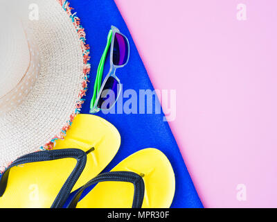 Les lunettes de l'été avec chapeau, tongs et serviette bleu sur fond rose.Locations et voyage d'été, détente concept. Banque D'Images