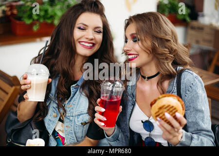 Portrait of cheerful gorgeous women enjoying limonade et café et des hamburgers dans les fast food cafe. Banque D'Images