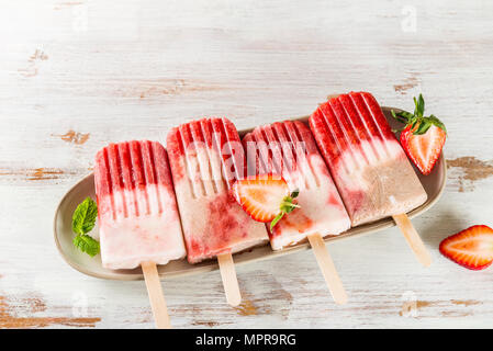 Vegan fait maison de Popsicle Fraise Jus de fraises et le lait de coco sur fond de bois clair. Concept des aliments en été. Vue d'en haut. Banque D'Images