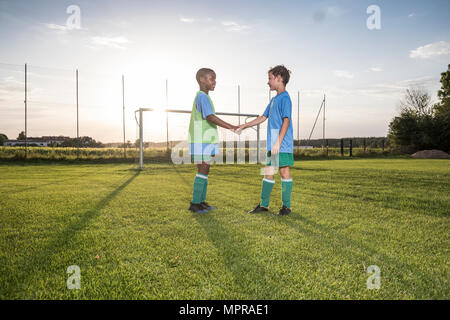 Jeunes joueurs de football se serrer la main sur terrain de football Banque D'Images