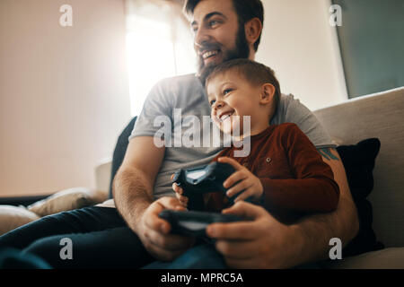 Heureux père et petit fils assis ensemble à la table de jeu d'ordinateur de jeu Banque D'Images