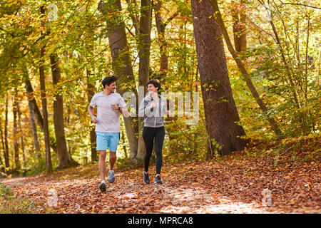 Couple jogging sur la piste forestière autumnally Banque D'Images