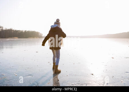 Allemagne, Brandebourg, lac Straussee, vue arrière d'un fille qui marche sur le lac gelé Banque D'Images