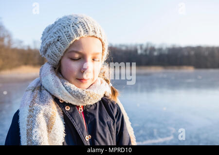 Allemagne, Brandebourg, lac Straussee, portrait d'une jeune fille debout sur le lac gelé, les yeux fermés Banque D'Images