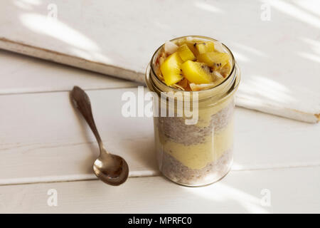 Verre de chia pudding à la mangue smoothie garni de flocons de noix de coco et kiwi Banque D'Images