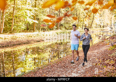 Couple jogging sur la piste forestière autumnally Banque D'Images