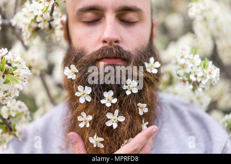 Portrait de hipster avec arbre blanc fleurs dans sa barbe Banque D'Images