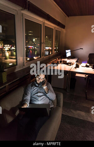 Businessman in office assis sur la table de nuit à l'aide d'ordinateur portable et un casque Banque D'Images