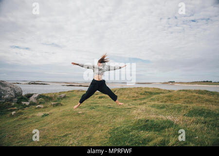 France, Bretagne, Landeda, les Dunes de Sainte-Marguerite, jeune femme sautant sur la côte Banque D'Images