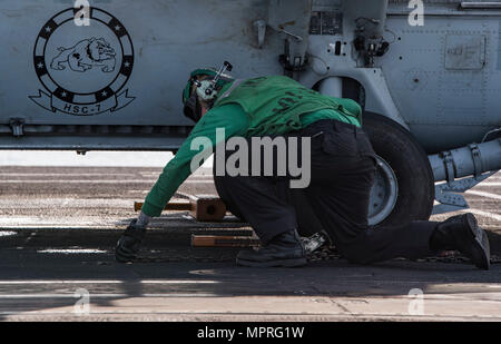 170412-N-QI061-065 OCÉAN ATLANTIQUE (12 avril 2017) l'Aviation-électricien 2e classe Daniel Henson, de Austin, Texas, supprime les chaînes et des cales d'un MH-60S Sea Hawk affecté à l'hélicoptère de chiens poussiéreux de l'Escadron de Combat de mer (HSC) 7 sur le pont d'envol du porte-avions USS Dwight D. Eisenhower (CVN 69) (Ike). Ike et son groupe aéronaval sont en cours participant à un exercice de soutien conçus pour maintenir la disponibilité du déploiement dans le cadre du Plan d'intervention de la flotte optimisée (OFRP). (U.S. Photo par marine Spécialiste de la communication de masse de la classe 3ème Nathan T. Barbe) Banque D'Images