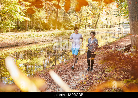 Couple jogging sur la piste forestière autumnally Banque D'Images