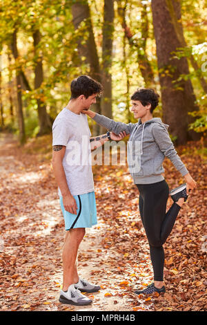 Couple stretching en forêt d'automne Banque D'Images