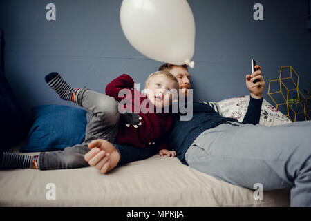 Père lecture des sms, tandis que son fils joue avec un ballon Banque D'Images