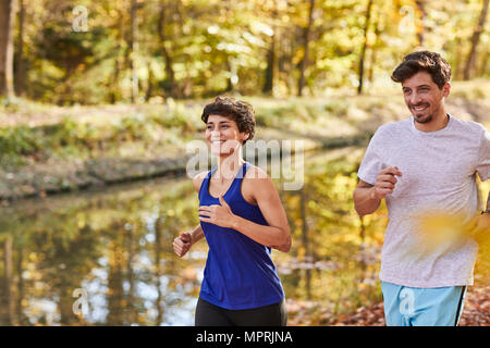 Couple jogging sur la piste forestière autumnally Banque D'Images