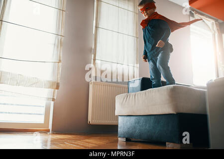 Petit garçon habillé en super héros jouant à la maison Banque D'Images