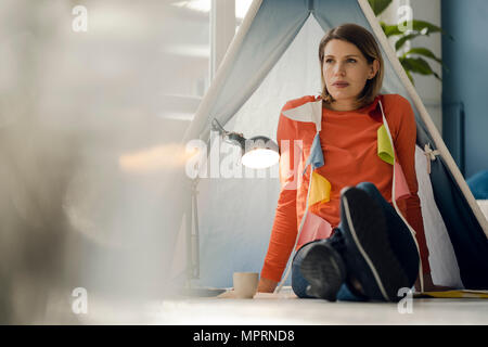 Femme assise sur le sol dans une tente dans son salon, à déçu Banque D'Images