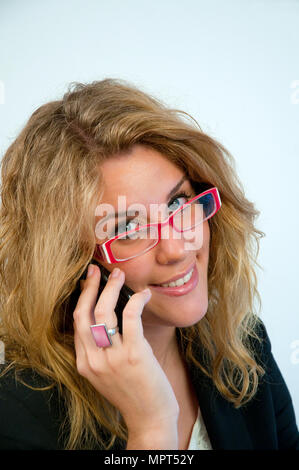 Jeune femme portant des lunettes, regardant la caméra et à l'aide de téléphone mobile. Voir de très près. Banque D'Images