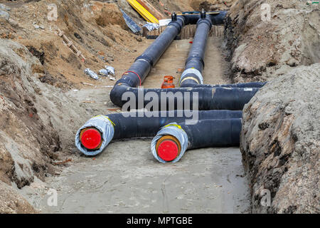 L'installation de conduites de chauffage urbain dans une tranchée, forage tuyau isolé. Banque D'Images