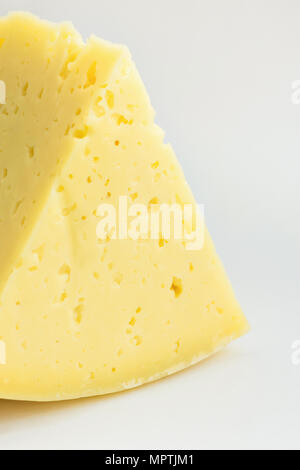 Gros morceau De Wedge crémeux Alpine jaune appétissant Fromage Tilsit sur fond blanc. Texture avec fissures et trous. Style minimaliste. Affiche Banque D'Images