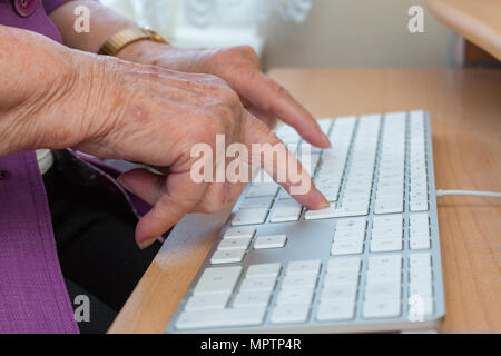 Close-up of a 95-year-old woman's old mains tapant sur un clavier d'ordinateur Banque D'Images