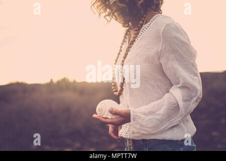 Nice couper pour belle l'âge moyen de 40 ans modèle immergé dans la nature d'un désert. elle prendre un shell sur sa main pour la nature conce connexion Banque D'Images