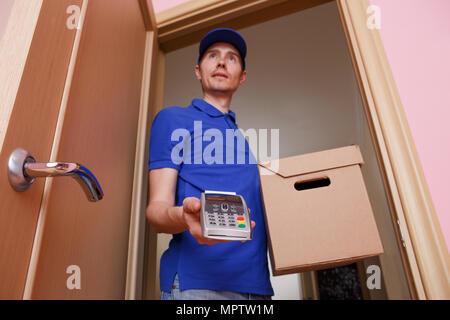 Photo de l'homme de courrier avec boîte en carton dans les mains et avec terminal Banque D'Images